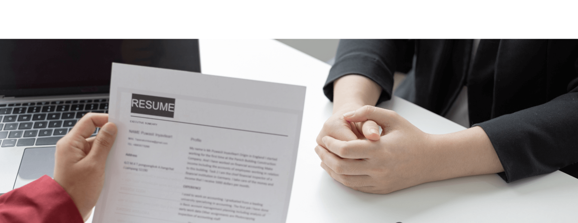 interview in progress with close up view of resume and attendees hands on white table