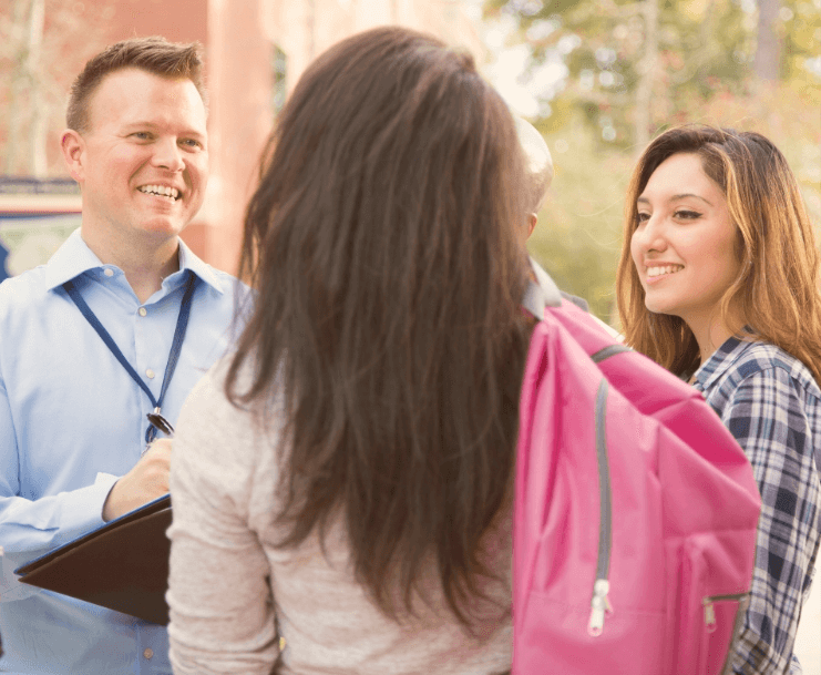 student with backpack speaking with tour guides on campus